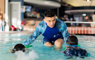 Swimming instructor helping children float in water